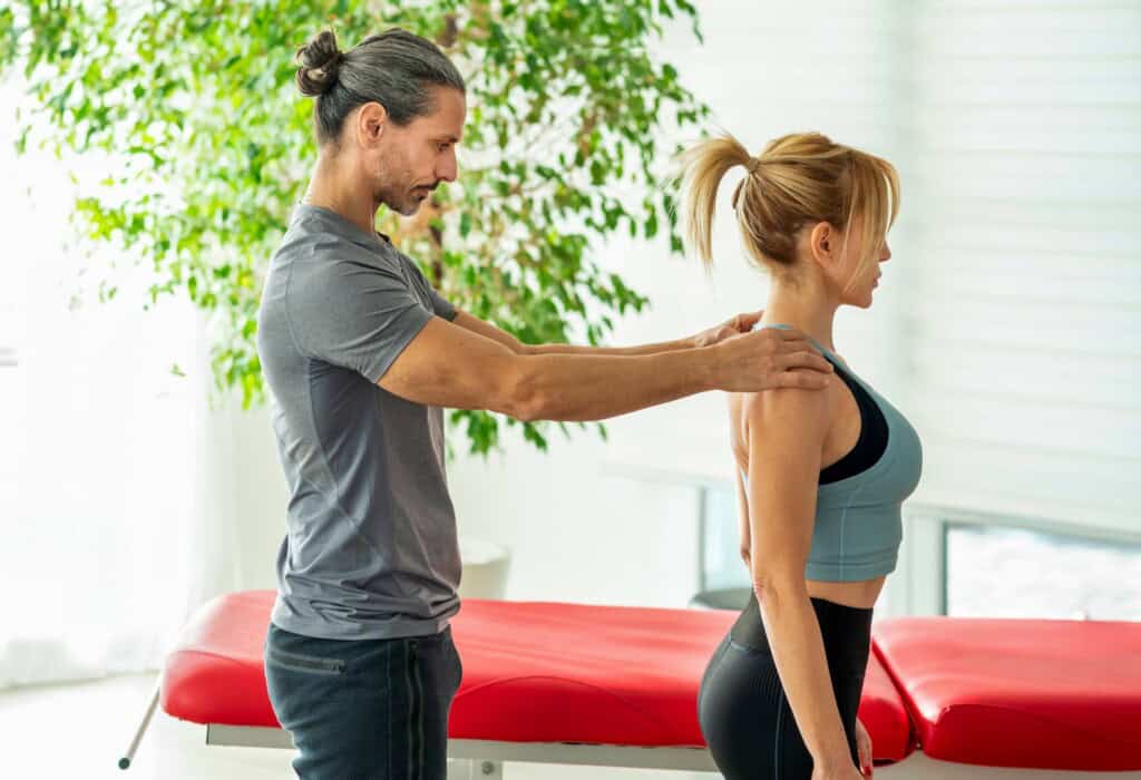 Male therapist performing postural evaluation on female client.
