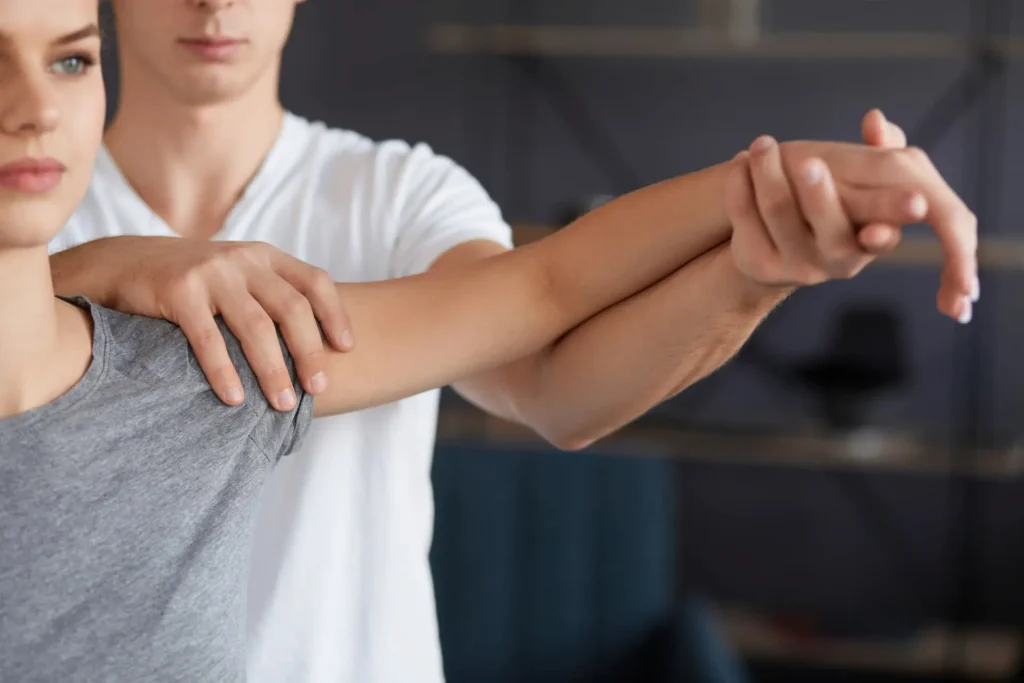 Therapist guiding a woman through a gentle shoulder stretch during a rotator cuff recovery session.