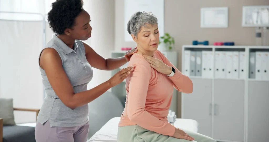 Therapist assessing a senior woman’s shoulder in a clinical setting to evaluate pain and mobility related to a possible rotator cuff injury.