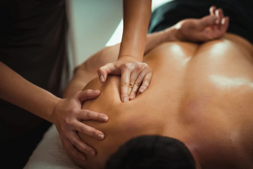 Massage therapist performing deep tissue bodywork on a client’s shoulder to treat a rotator cuff injury.