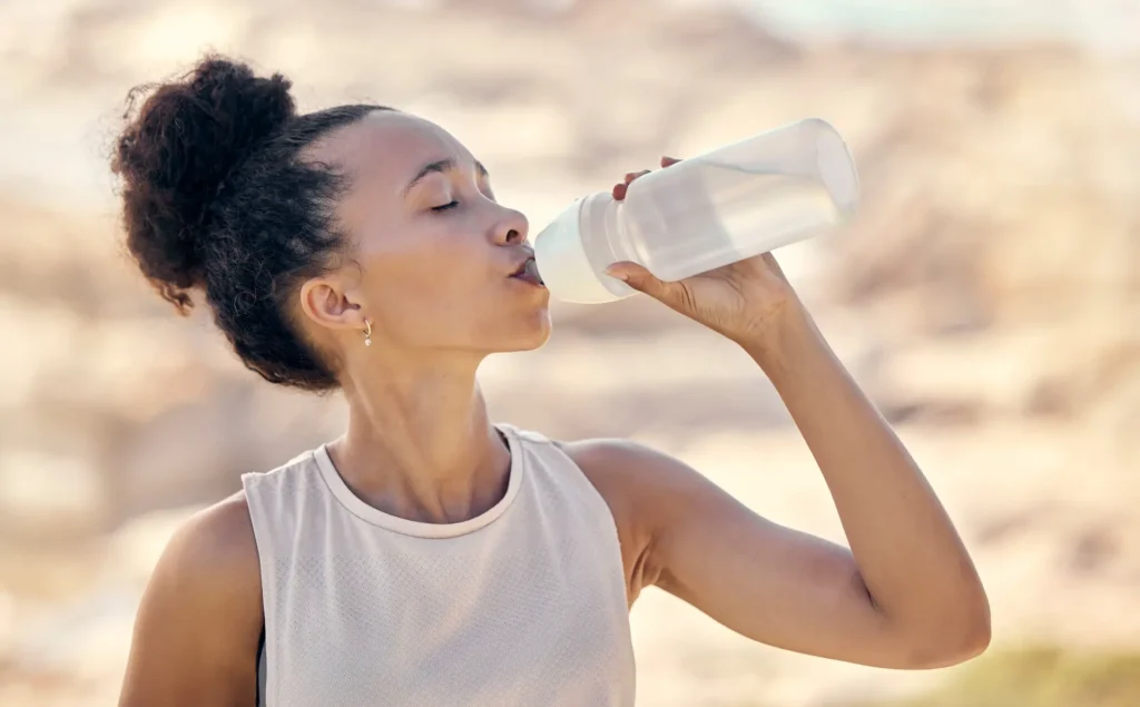 Woman drinking water after exercise to support fascia health and enhance the effectiveness of bodywork for cellulite reduction.