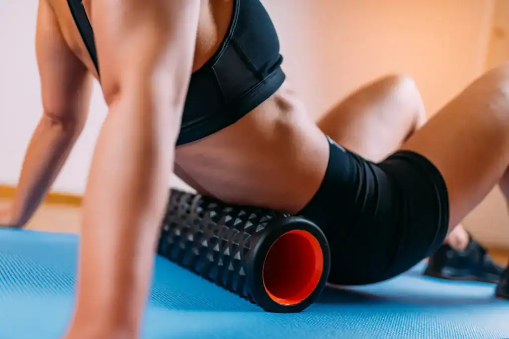 Woman using a textured foam roller on her glutes to relieve tension and support bodywork for Sacroiliac Joint Pain.