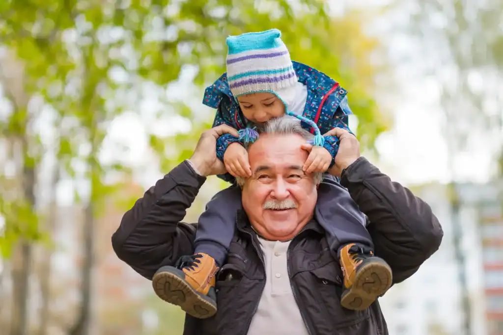 How We Use Gua Sha Massage Therapy to Break Up Pain and Restore Movement 5 Smiling grandfather carrying his grandchild on his shoulders during a walk.