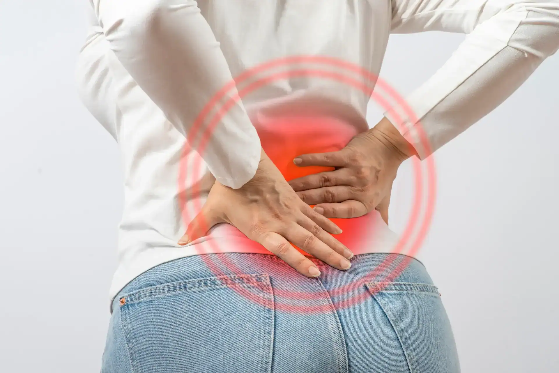 Person holding lower back in pain, highlighting the L5-S1 area often affected by lumbosacral dysfunction.