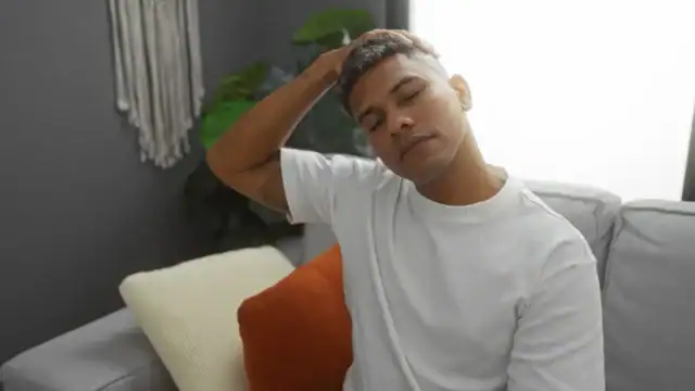 Man sitting calmly on a couch with his hand resting on his head, at ease after a bodywork session.